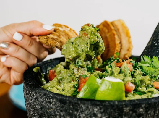 Fresh guacamole in a molcajete with tortilla chips