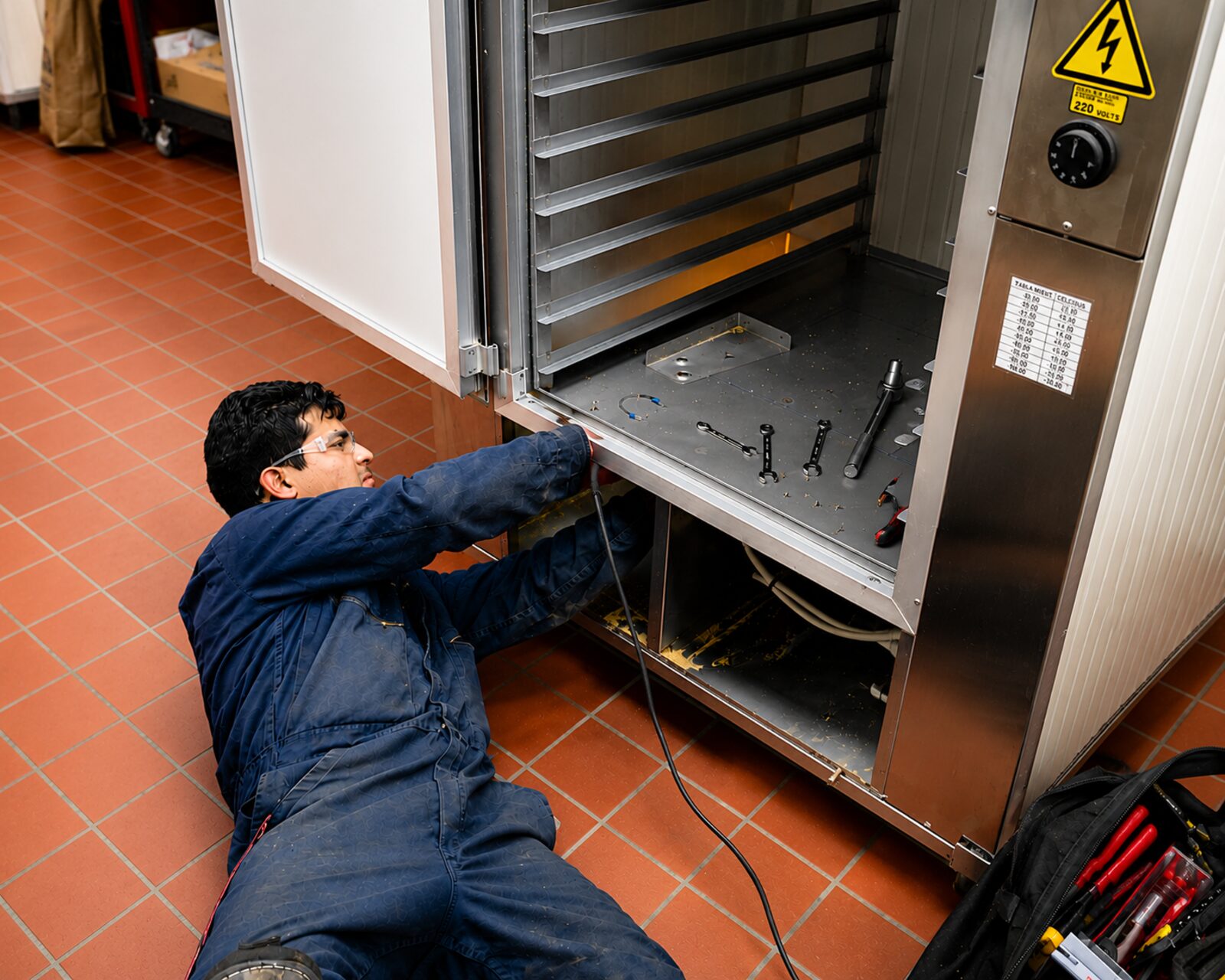 A technician repairing a commercial oven in a local business kitchen